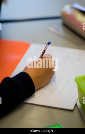 Secondary Education in the UK: close up of the hand of a pupil writing in their exercise book note books in a  maths math mathematics class lesson Stock Photo