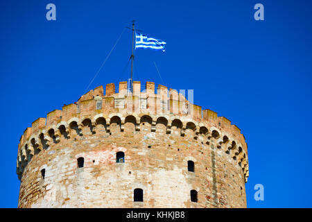 The White Tower in Thessalonica and waving Greek flag, Greece Stock Photo