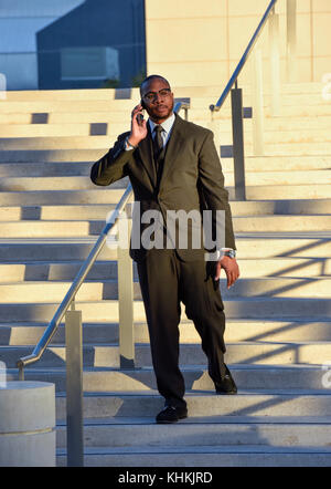 Black American businessman walking down steps in front of a downtown business. Stock Photo