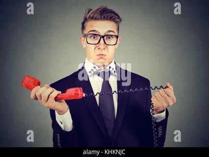Shocked disgusted young man receiving bad news over the phone Stock Photo