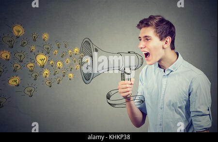 Man screaming out his ideas loud in megaphone isolated on gray wall background Stock Photo