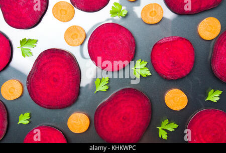 Raw beet and carrot slices isolated on dark background Stock Photo