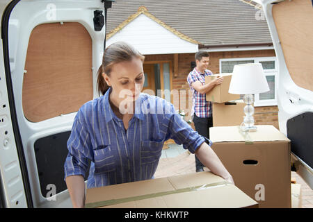 Young Couple Moving In To New Home  Unloading Removal Van Stock Photo