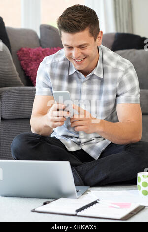 Male Freelance Worker Using Mobile Phone At Home Stock Photo