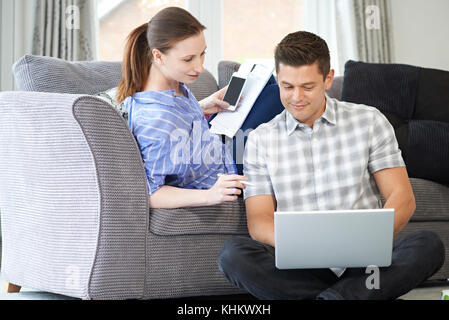 Freelance Couple Working From Home Looking At Laptop Together Stock Photo