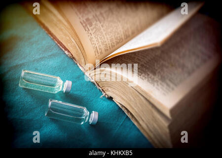Vials with medication next to an old book of medicine, conceptual image Stock Photo