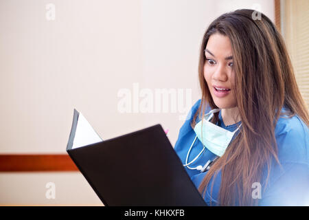Close-up photo of surprised female hispanic doctor looking into her folder in hospital hallway Stock Photo