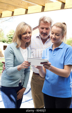 Mature Couple Discussing Plan With Landscape Gardener Using Digital Tablet Stock Photo