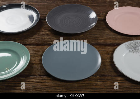 Close-up of various empty plates on wooden plank Stock Photo