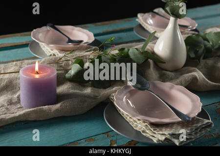 Elegance table setting with flower vase and lit candle on table Stock Photo