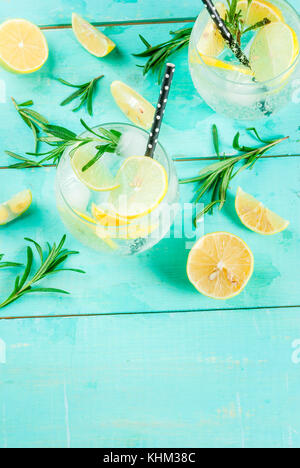 Cold lemonade or alcohol vodka cocktail with lemon and rosemary, on light blue table, copy space Stock Photo