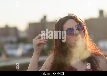 Portrait of a young woman in sunglasses on a roof Stock Photo