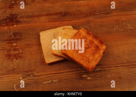 Three slices of toast, each toasted for a longer time, on a wood surface in landscape format with copy space Stock Photo
