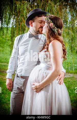 Photo of a pregnant bride and groom kissing during the wedding ceremony. Stock Photo