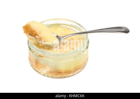 Lemon cheesecake in a glass ramekin with a spoon isolated against white Stock Photo