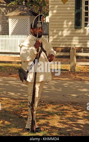 A soldier in period dress stands at attention with musket at his side on the Palace Green in Colonial Williamsburg in the beautiful state of Virginia Stock Photo