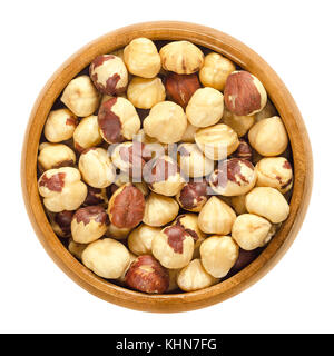 Roasted hazelnuts in wooden bowl. Crisp toasted nuts of the hazel. Shelled whole seeds of cobnuts or filbert nuts, Corylus avellana. Macro food photo. Stock Photo