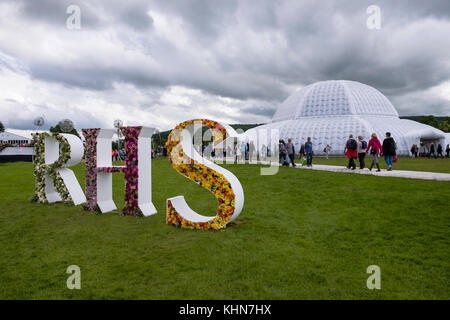 RHS Chatsworth Flower Show - Great Conservatory marquee & people passing floral display on RHS initials - Chatsworth House, Derbyshire, England, UK. Stock Photo