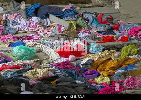 Abandoned heap of old worn clothes. Scattered colorful fabric. Stock Photo