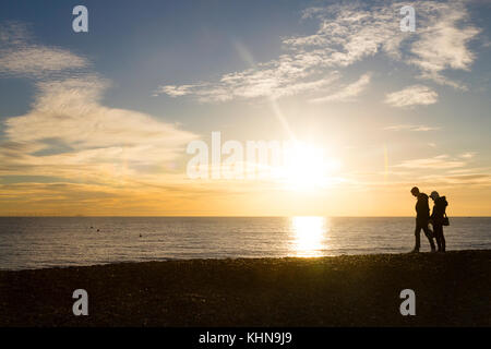 Brighton, UK. A young couple walk along Brighton beach at sunset. Stock Photo