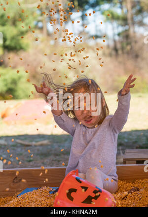 Young girl playing in a sandpit made from corn cob seeds Stock Photo
