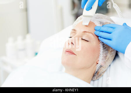 Woman with aging skin having facial care procedure while visiting beautician Stock Photo