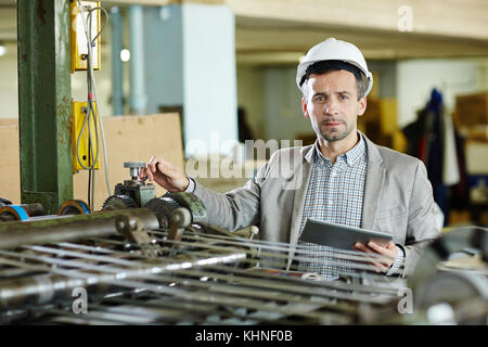 Foreman with touchpad working by industrial machine in modern factory Stock Photo
