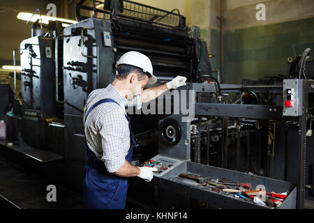 Factory master pressing button on panel of industrial machine during work Stock Photo