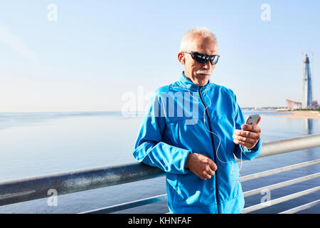 Aged sportsman in activewear and sunglasses making selfie by riverside Stock Photo