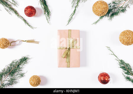 Box with gift and gold ribbon, spruce branches and Christmas decorations on a white table top view Stock Photo