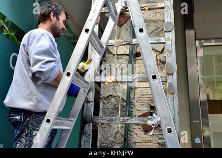 Workman on step ladder with gas torch working Stock Photo