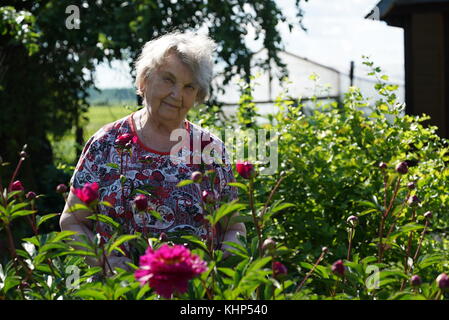 Portrait of old smiling woman in the park Stock Photo