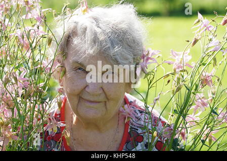 Portrait of old smiling woman in the park Stock Photo