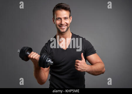 A handsome young man lifting weight smiling and showing thumbs up Stock Photo