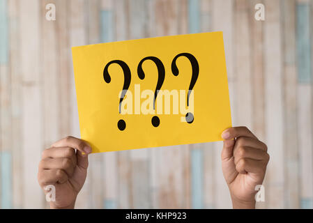 hand holding a paper note with question mark.question mark written on paper Stock Photo