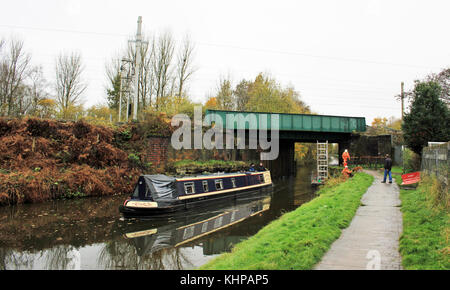 A narrow boat passes under the West Coast Main Railway line at Bamfurlong near Wigan as bridge inspectors for Network rail have moved out of the way. Stock Photo