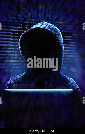 Unknown computer hacker with hood working on computer laptop in committing cyber crime on the Internet. Background data and dramatic lighting with cop Stock Photo