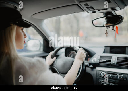 woman in car indoor keeps wheel turning around smiling looking at passengers in back seat idea taxi driver. Concept of exam Vehicle.