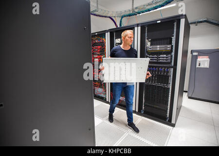 IT Consultant Carrying Blade Server While Walking In Datacenter Stock Photo