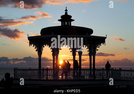 The setting sun silhouettes the Bandstand on Brighton seafront. Stock Photo