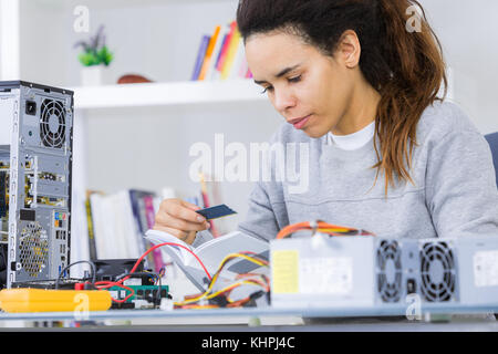 young female tech or engineer repairs electronic equipment Stock Photo