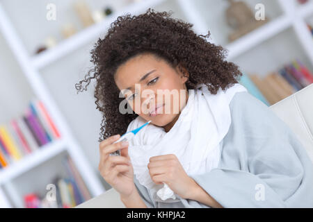Woman wrapped up warm taking her temperature Stock Photo