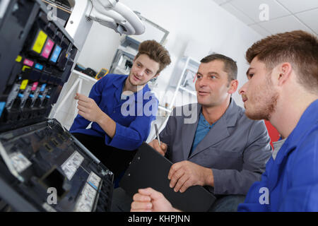 apprentices fixing photo copier Stock Photo