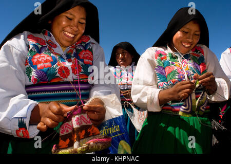 Amantani Island, Lake Titicaca, Puno, Peru. Several women from the island of Amantaní engaged in the work of weaving the colorful garments with which  Stock Photo