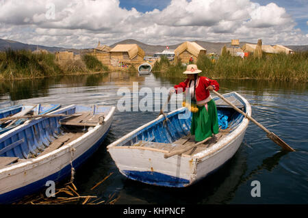 Uros Island, Lake Titicaca, peru, South America. A woman dressed in traditional regional dresses sails her boat between the Uros Islands. Stock Photo