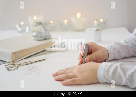 Close up photo of child´s hands holding scissors, cutting white paper, creating chrismas paper origami Stock Photo
