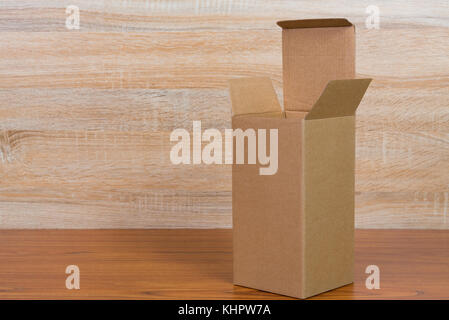 Empty opened brown cardboard box for mock up on bright wooden table with copy space. Stock Photo