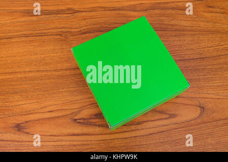 Empty closed green cardboard box for mock up on bright wooden table with copy space. Stock Photo