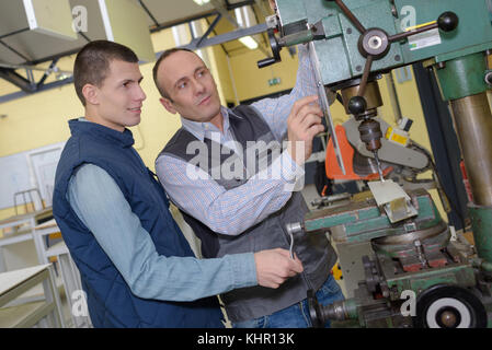 engineer and apprentice using automated milling machine Stock Photo