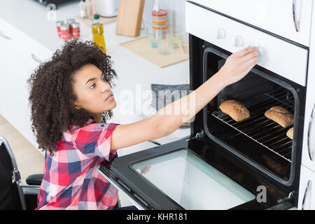 woman on the wheelchair reaching the oven knob Stock Photo